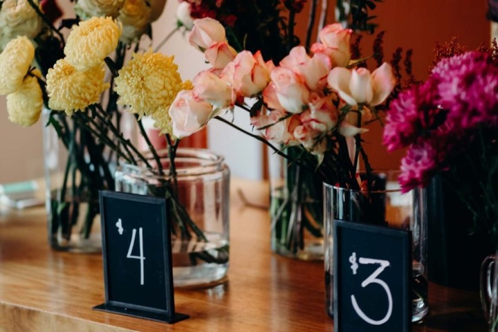 Vases of flowers on a table with price tags: $4 yellow blooms, $3 mixed pink and purple blooms.